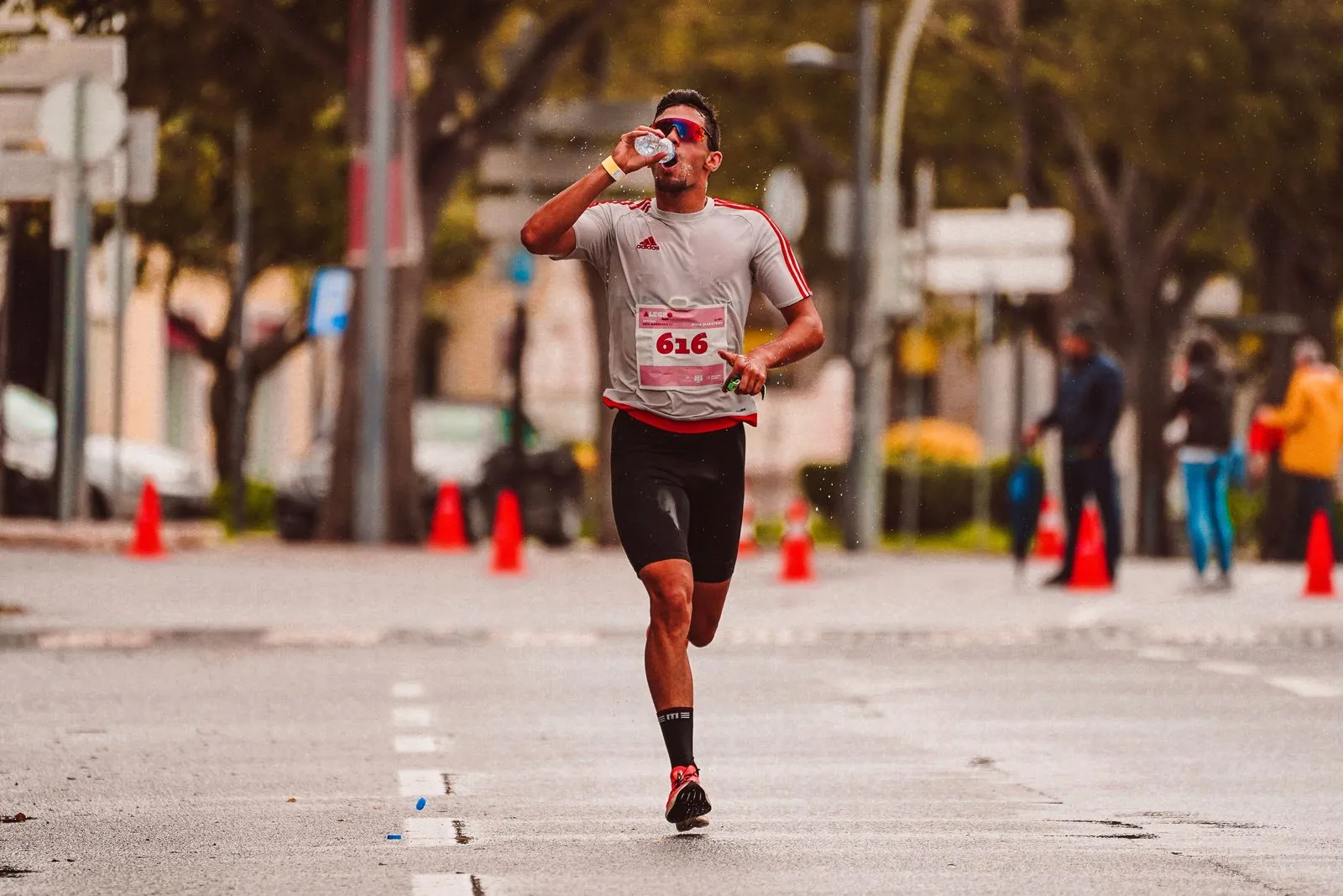 A runner drinking water during a road event