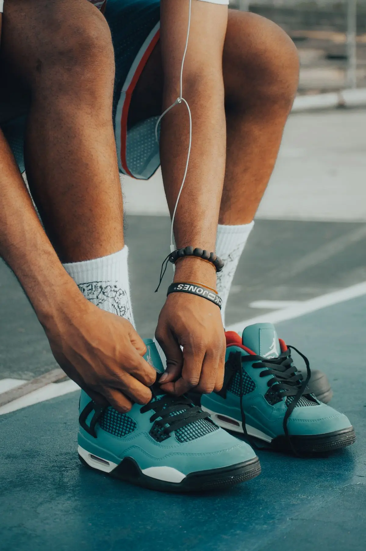 Close-up of a man tying his running shoes on an outdoor court.