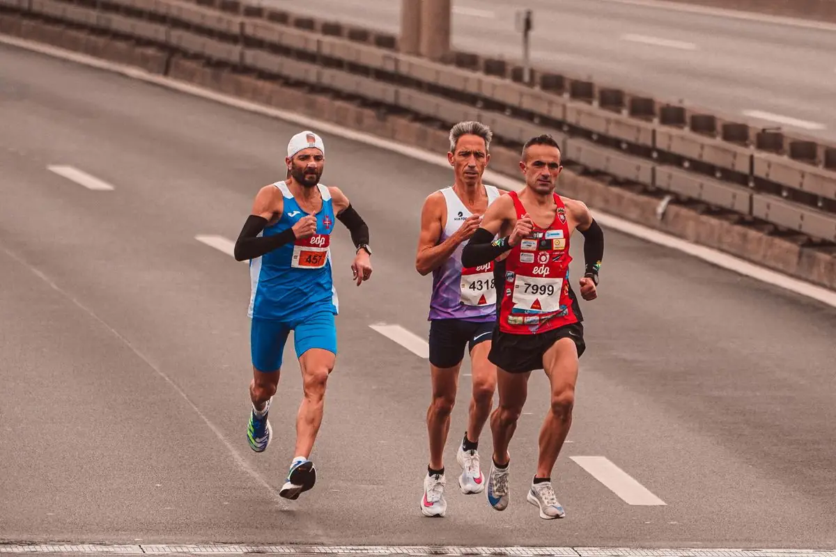 Three male marathon runners on a city street showcasing endurance and competition.
