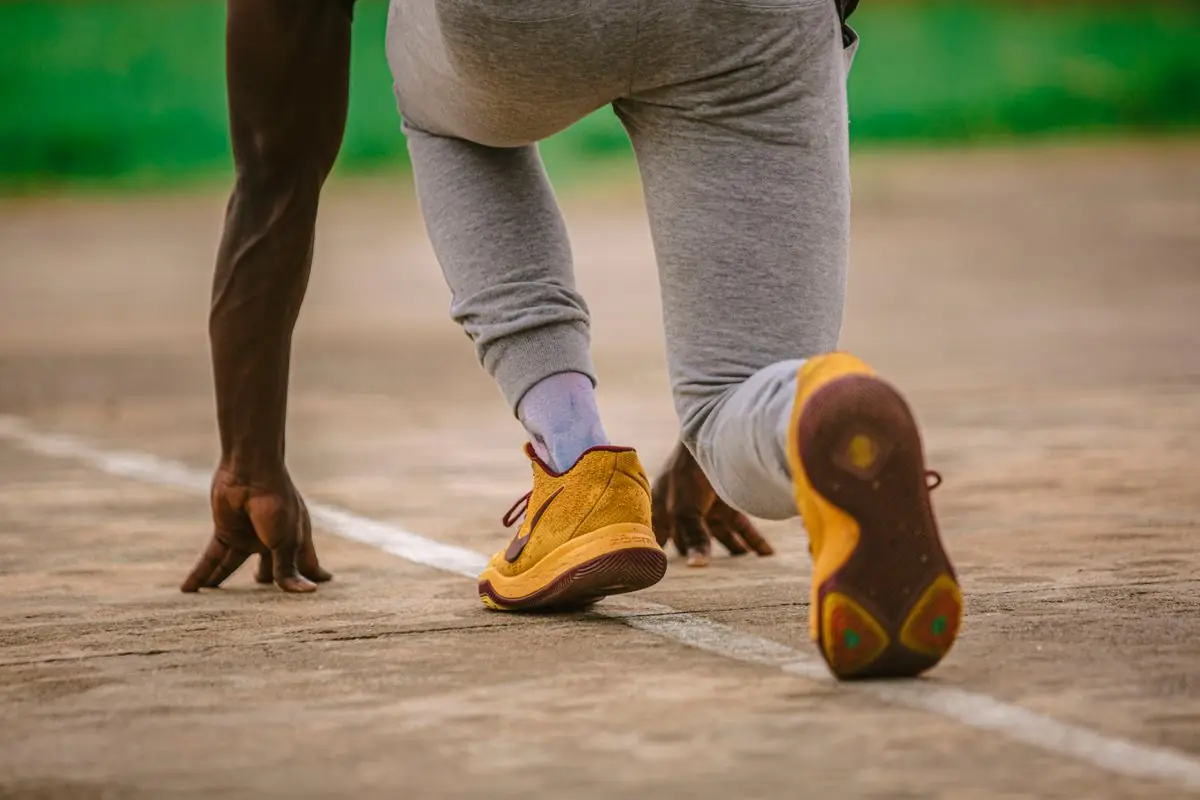 Close-up of an athlete in sportswear at the starting line on an outdoor track.