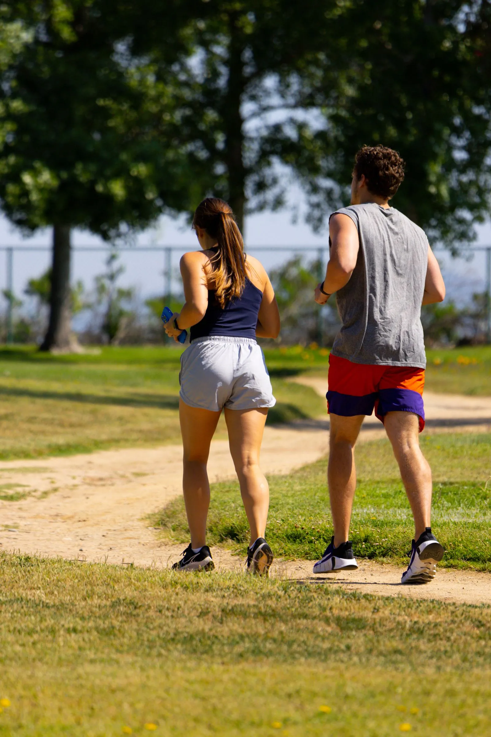 Two runners on a sunlit park path