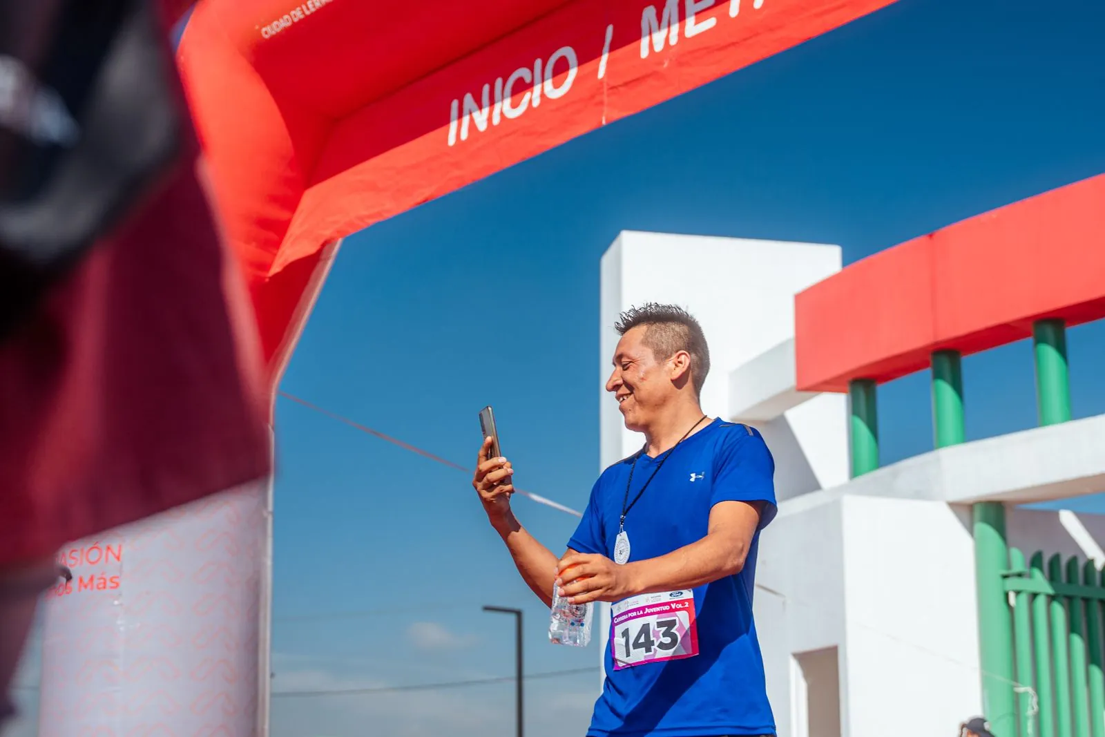 A runner carrying a phone and a water bottle