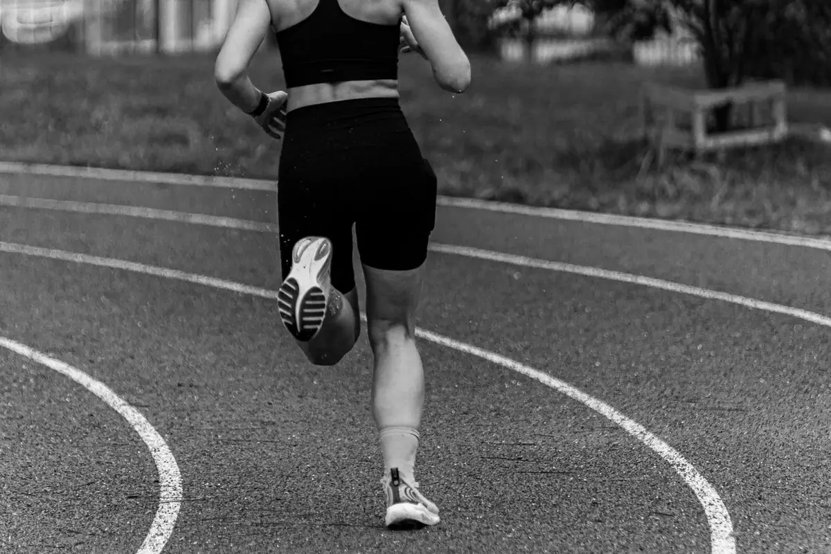 Dynamic black and white shot of a runner practicing on an outdoor track.