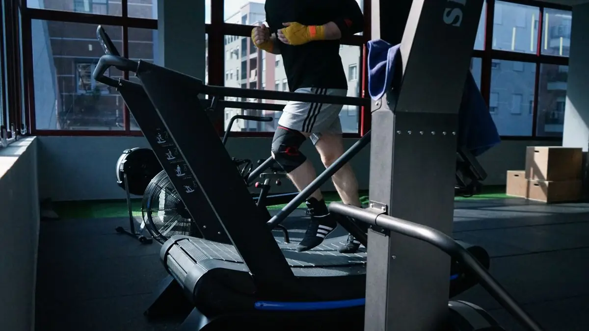 Adult man exercising on a treadmill in a modern indoor gym setting.