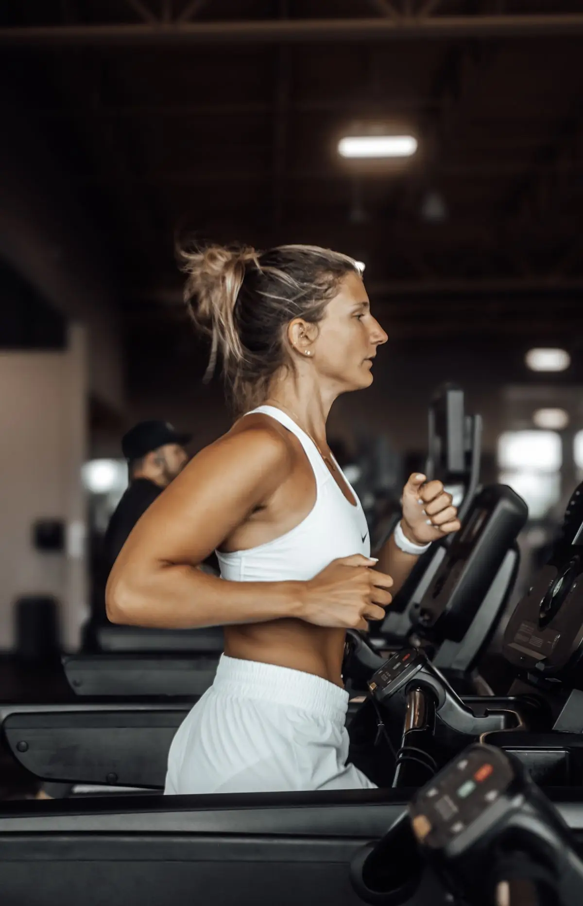 Athletic woman focused on her workout running on a gym treadmill.