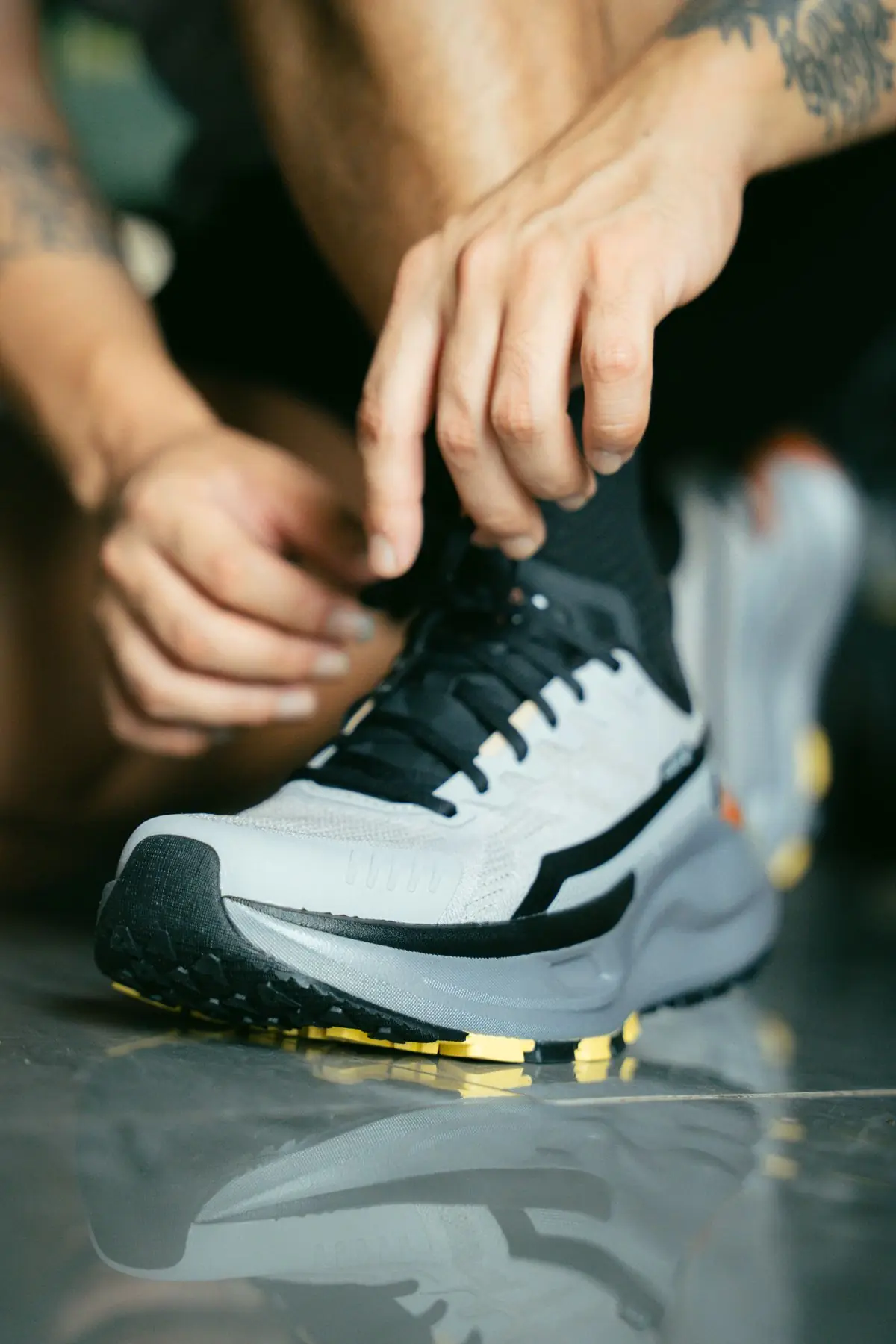 Focused close-up shot of an athlete tying the laces of a running shoe.