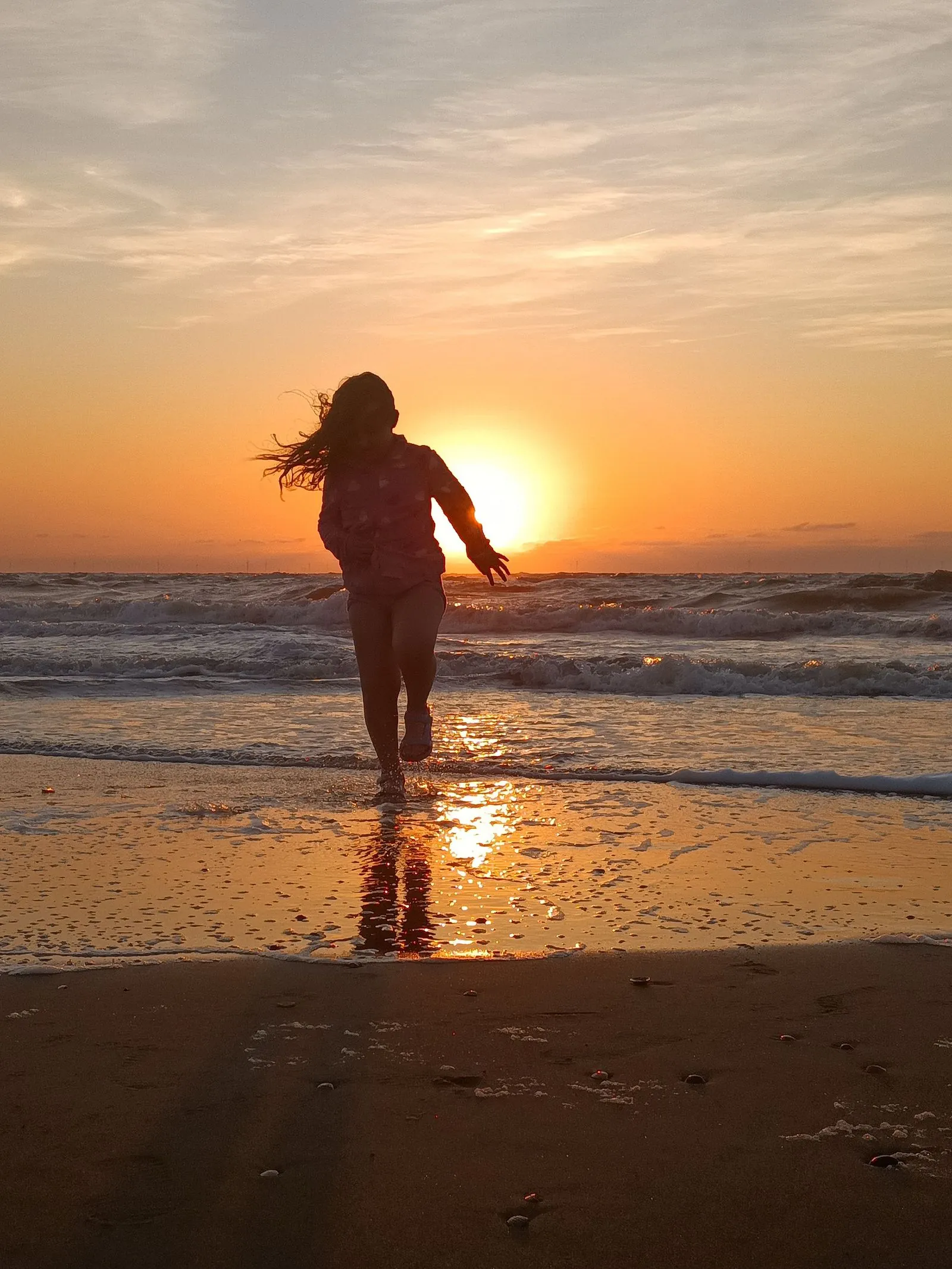 A runner silhouetted against the sunrise on a beach