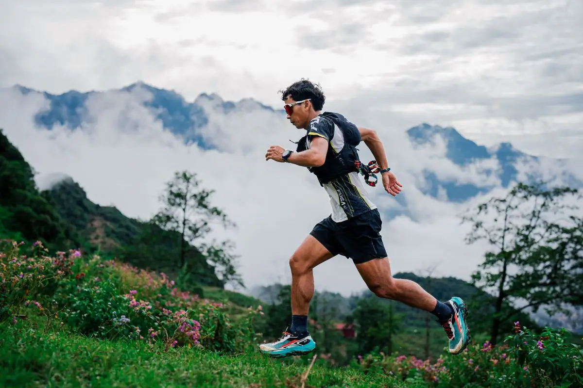 A runner dashes through a misty mountain trail.
