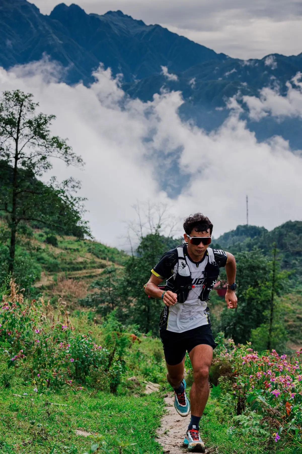 A trail runner climbing through a green mountain landscape
