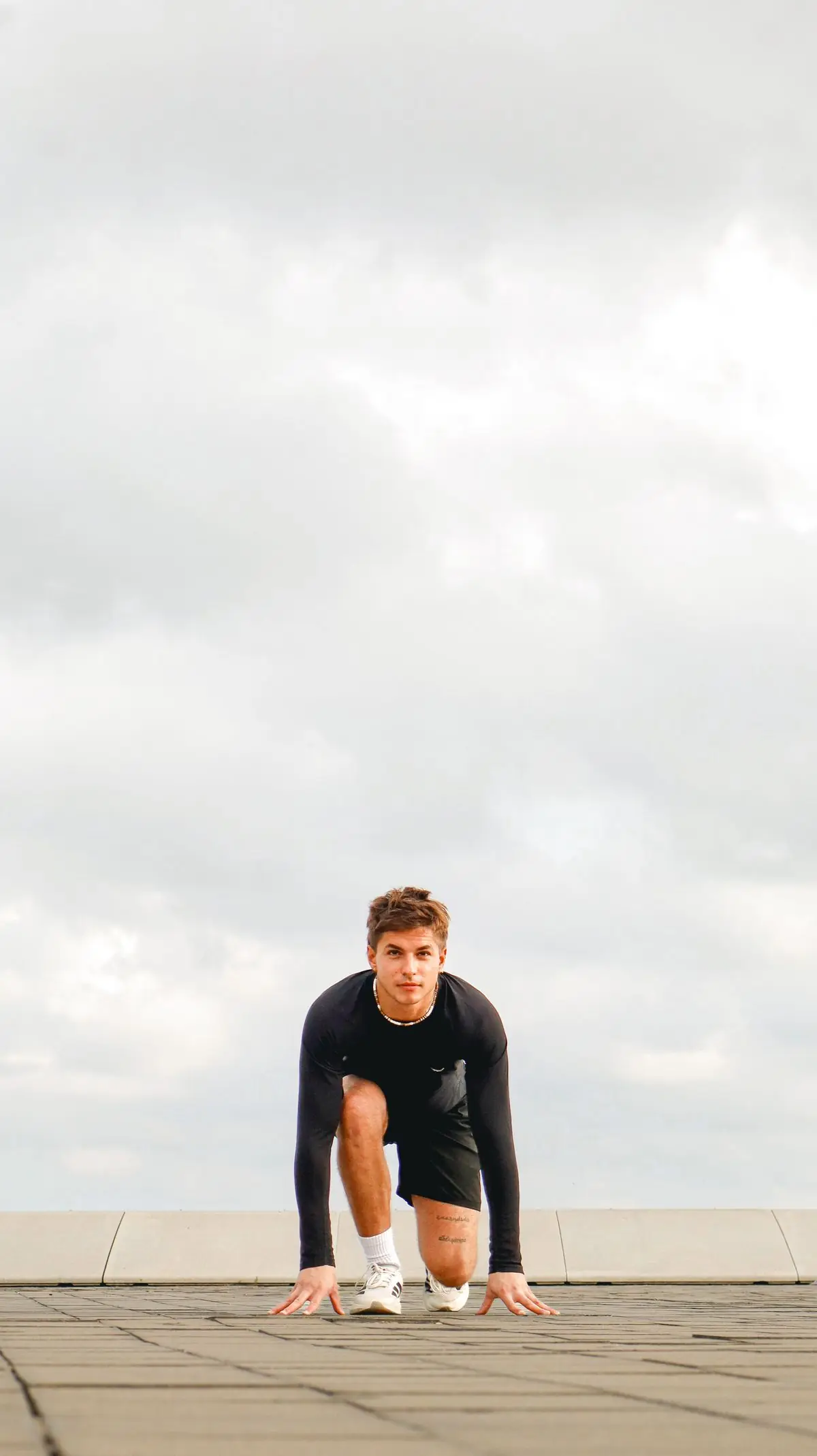 Focused athlete in a starting position on an outdoor track preparing for a sprint in España.