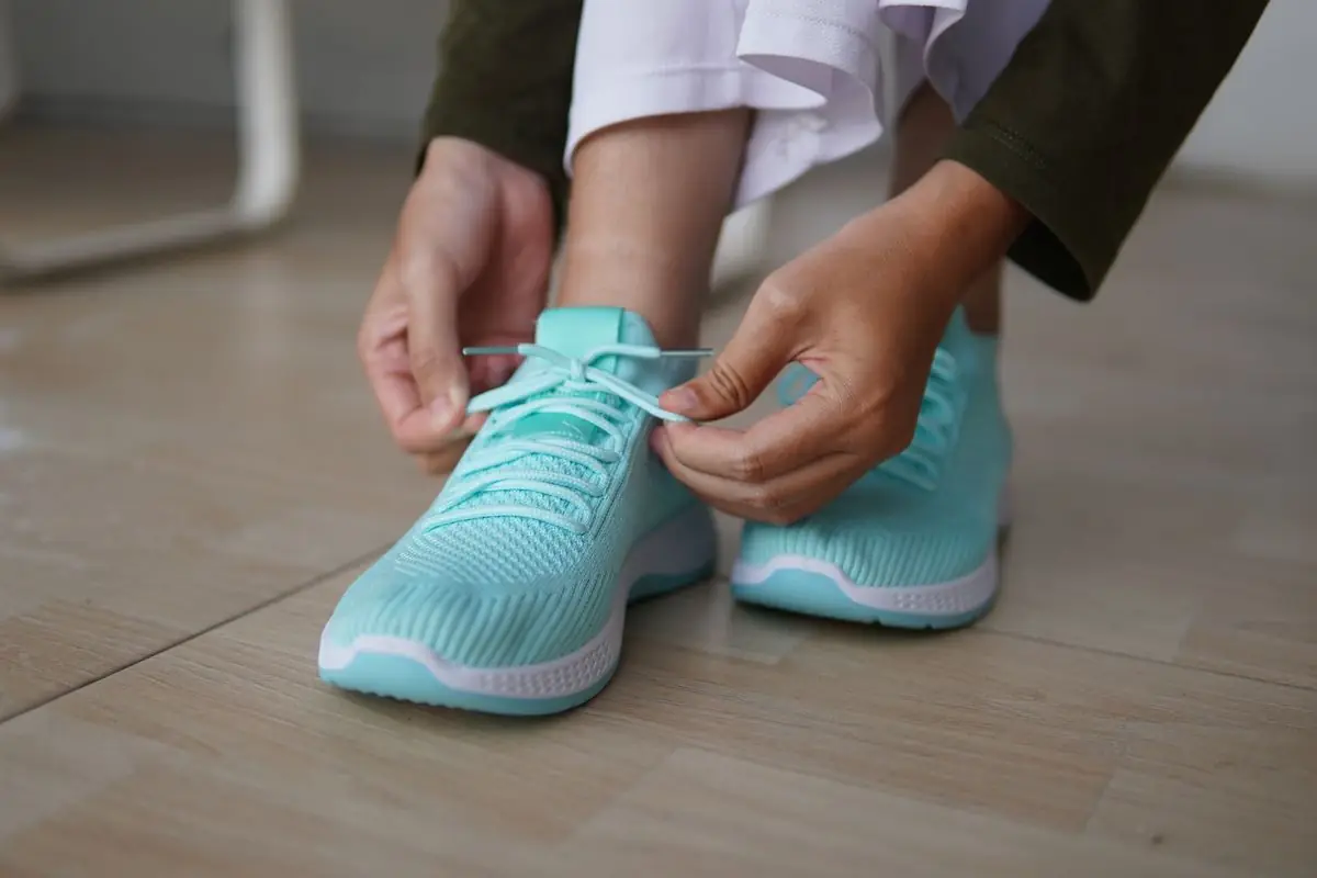 Close-up of hands tying shoelaces on vibrant blue running shoes.