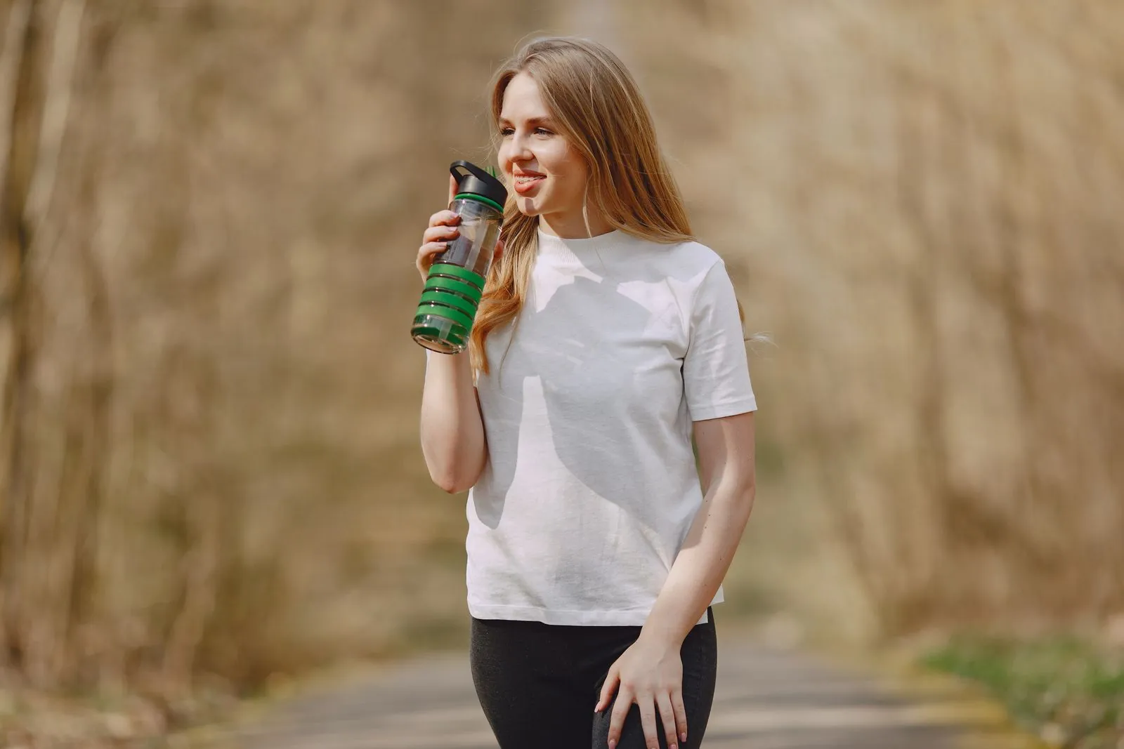 A woman drinking water during an outdoor exercise break