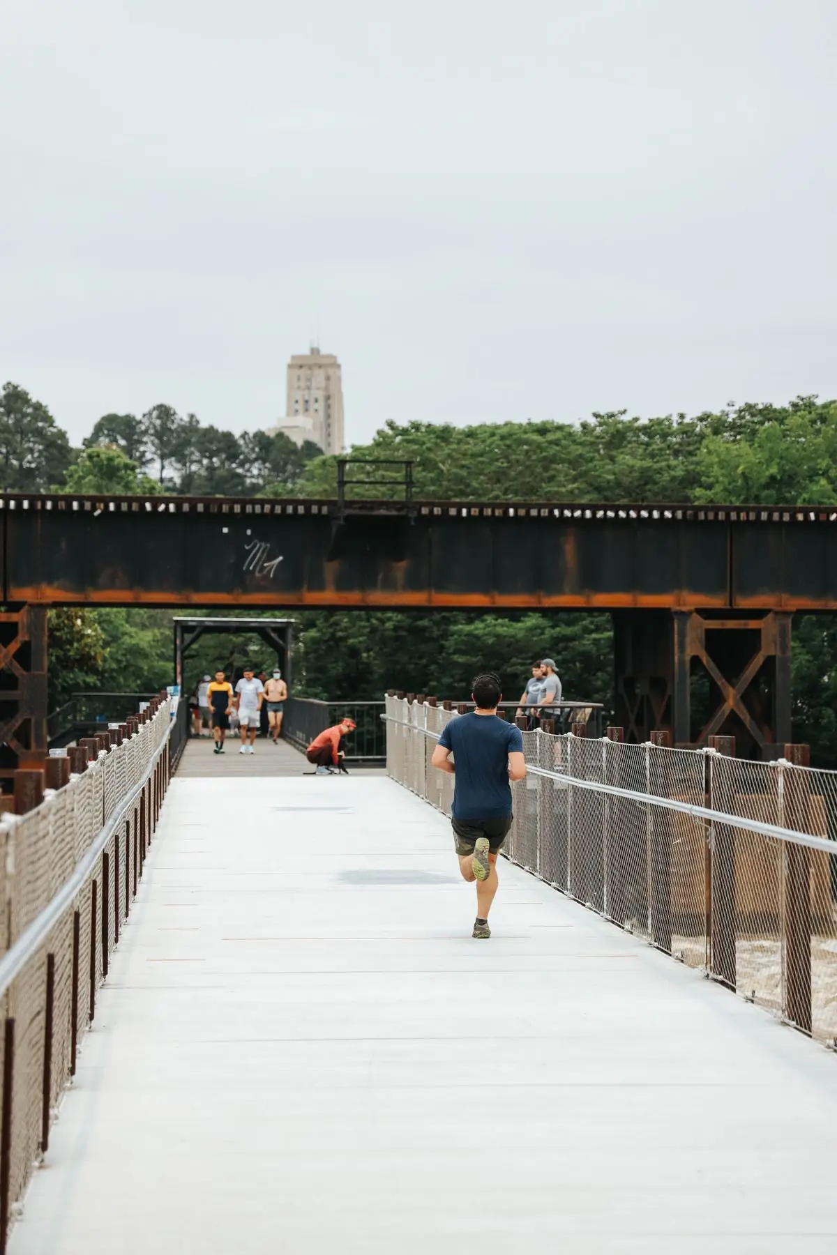 Man in comfortable wear running through bridge near park in daylight.