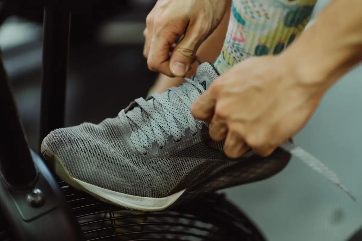Detailed shot of hands tying shoelaces on a gray running shoe.