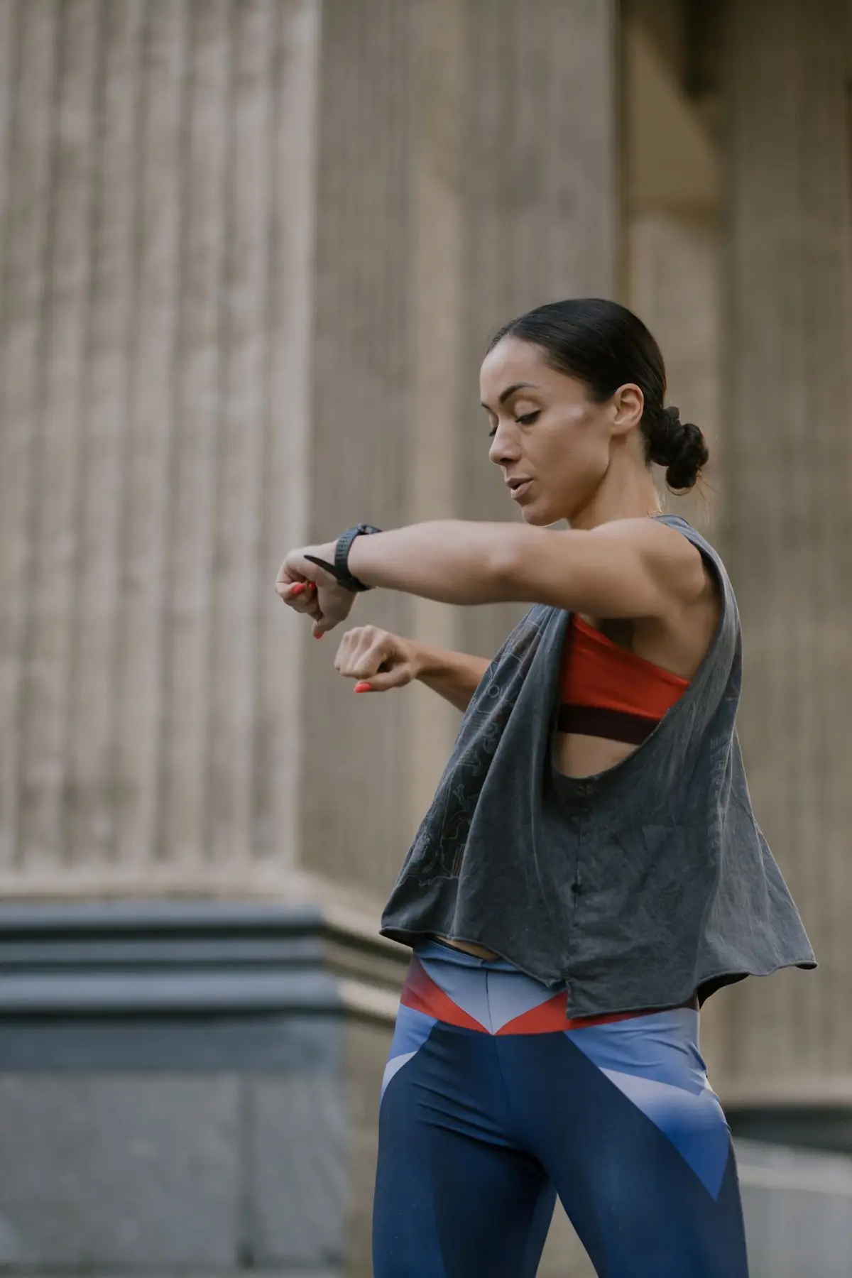 Woman in activewear checking her fitness tracker in an outdoor urban setting.