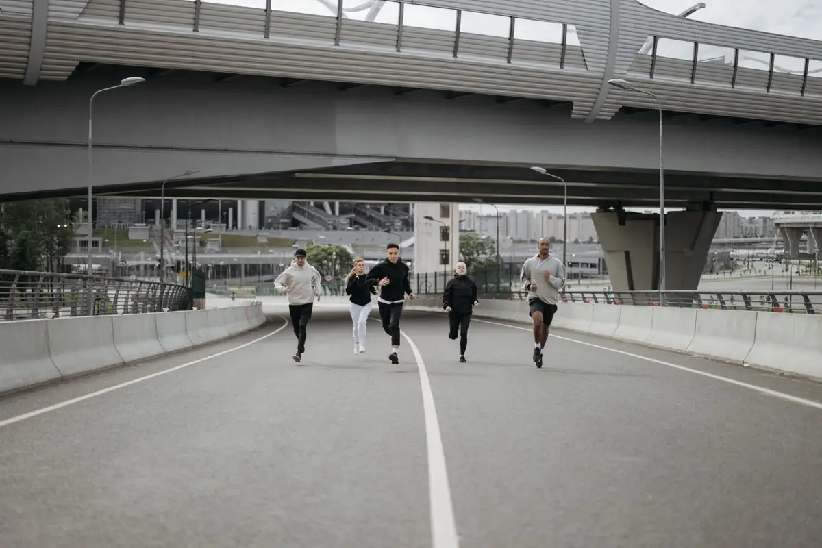 A diverse group of people running on a city road.