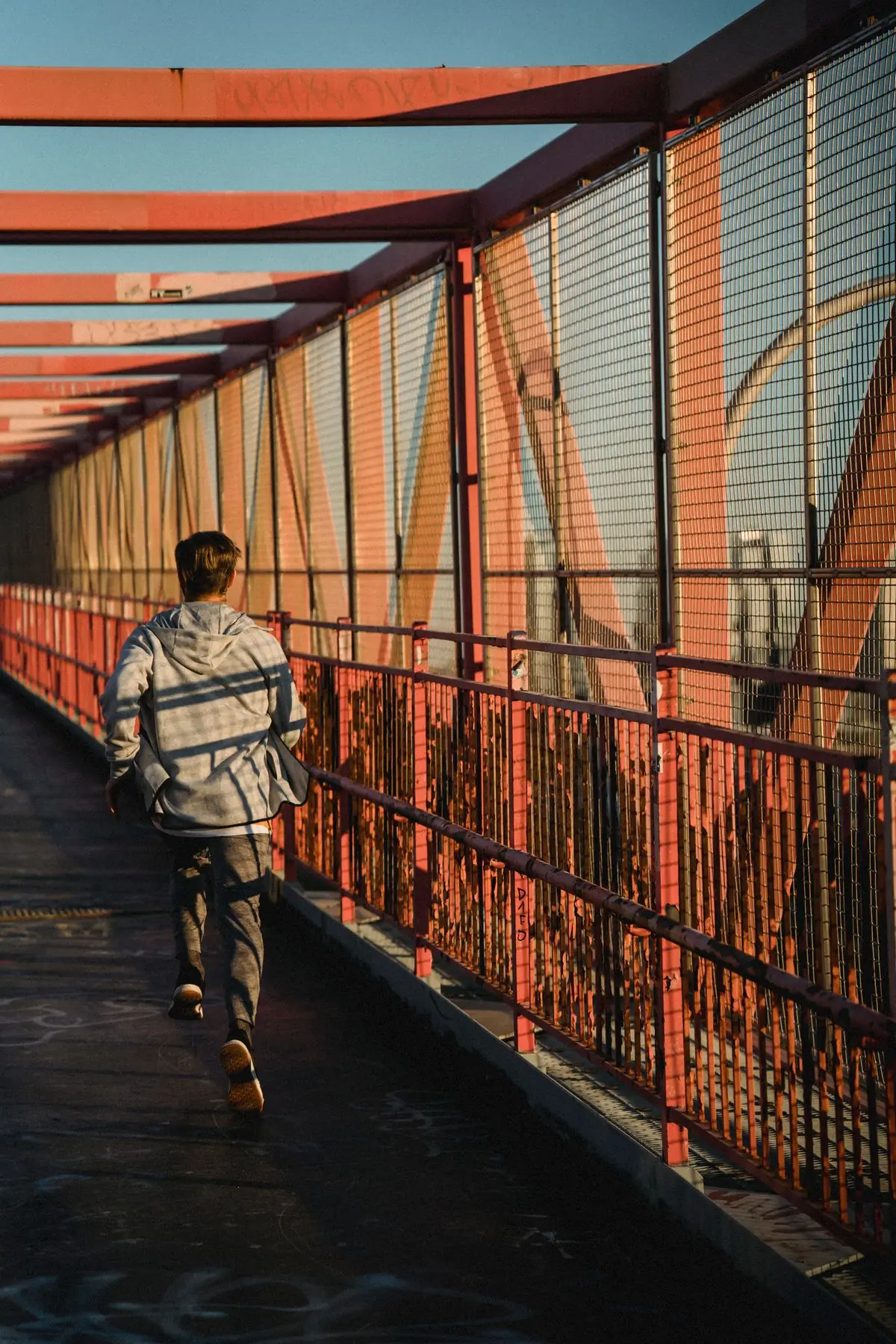 Unrecognizable fit sportsman running on roofed bridge during training in city.
