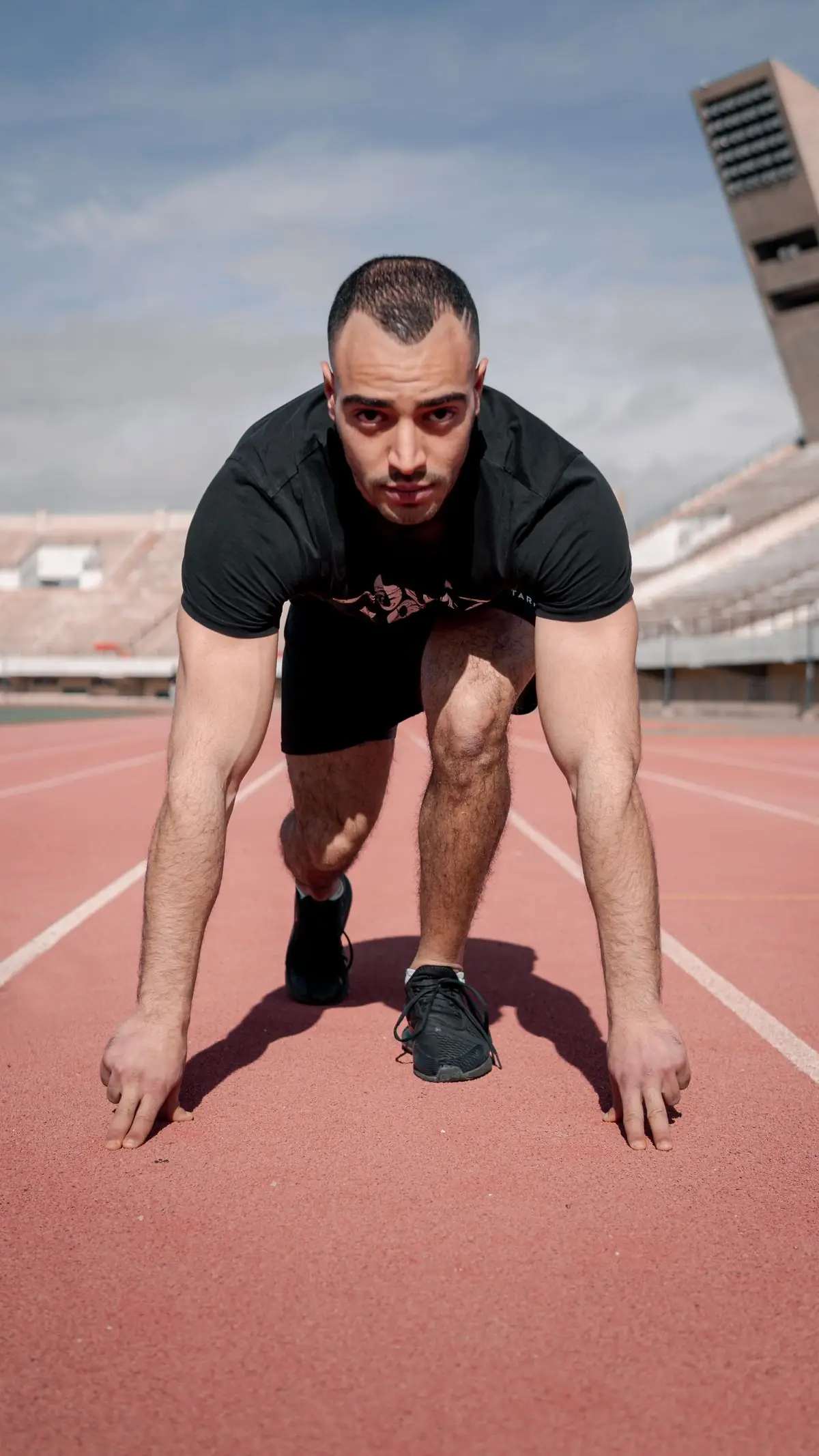 Focused young male athlete at starting line on outdoor track.