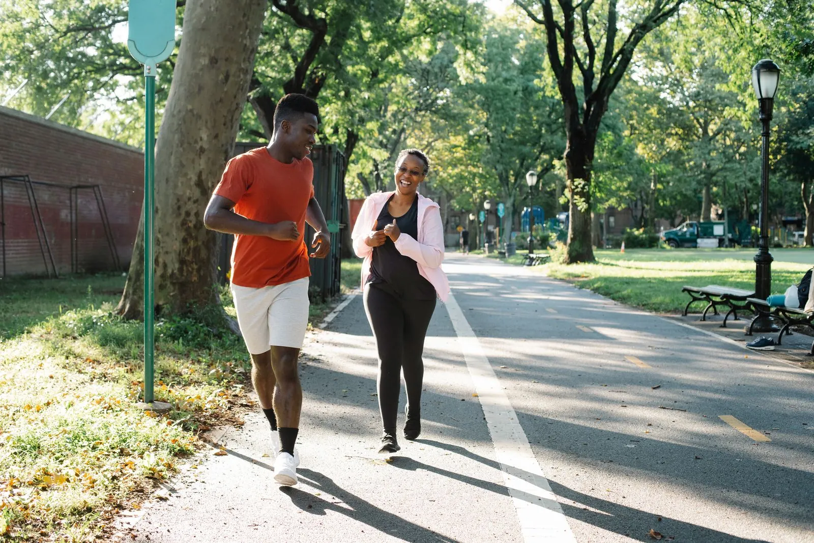 Two runners moving together through a green park