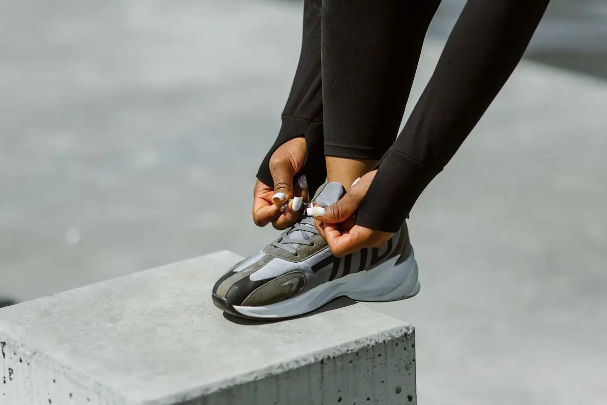 Focused photograph of hands tying athletic shoe laces outdoors.