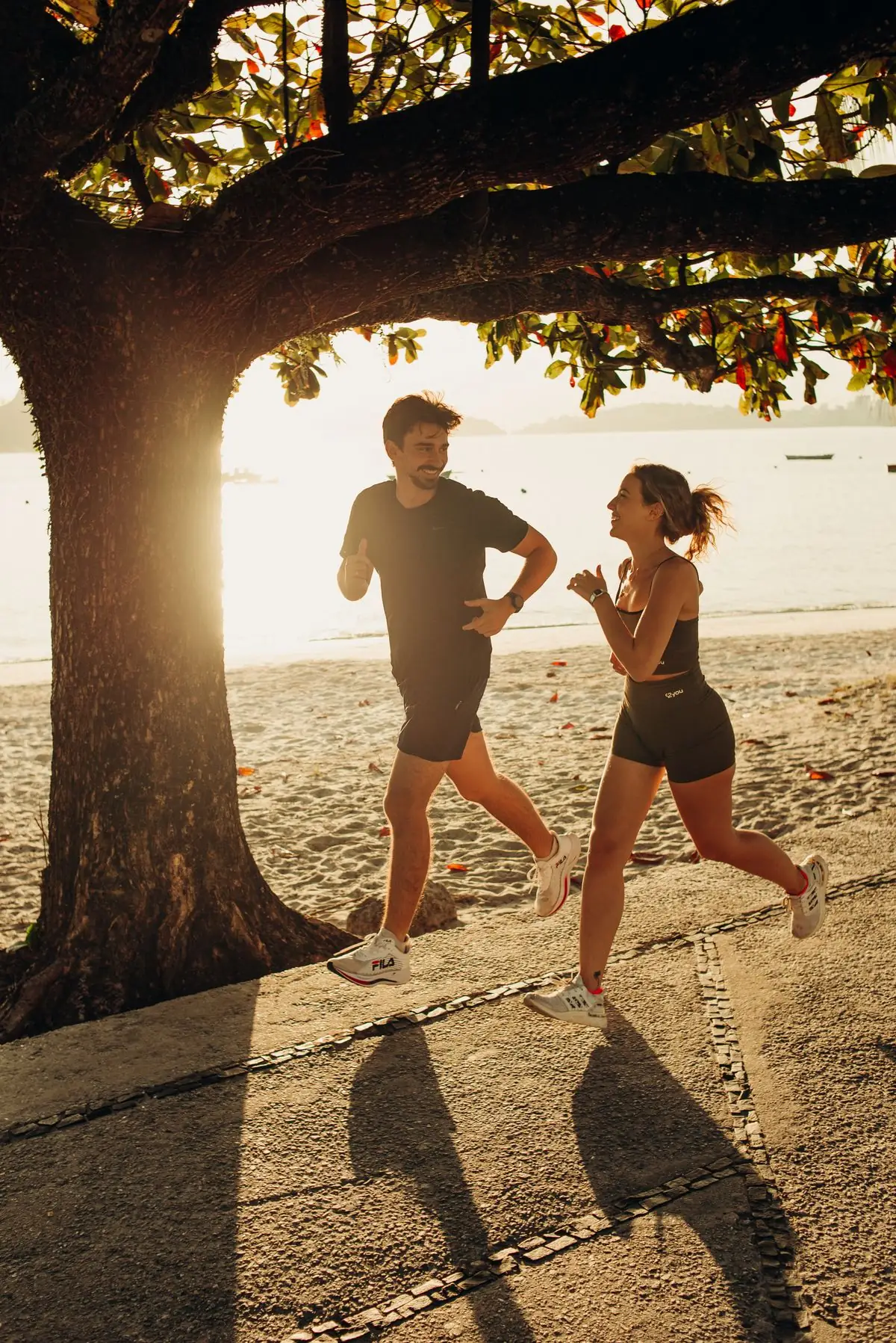 Two runners on a seaside path in warm sunlight